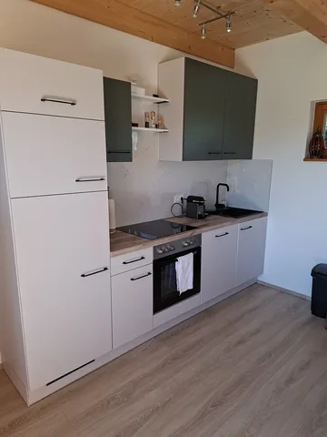 Küche mit hohen Schränken, schwarzer Armatur und heller Arbeitsfläche